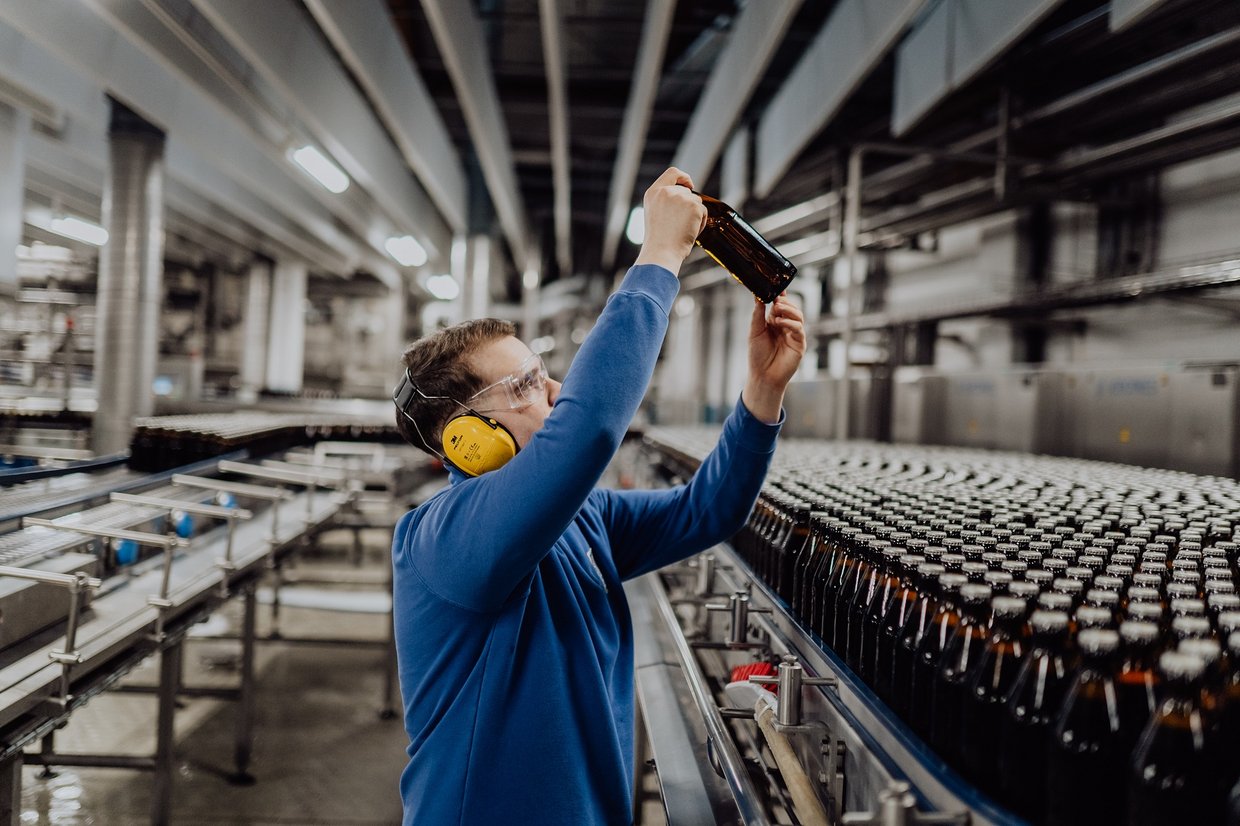 Mitarbeiter der Brauerei kontrolliert eine Flasche in der Flaschenabfüllerei