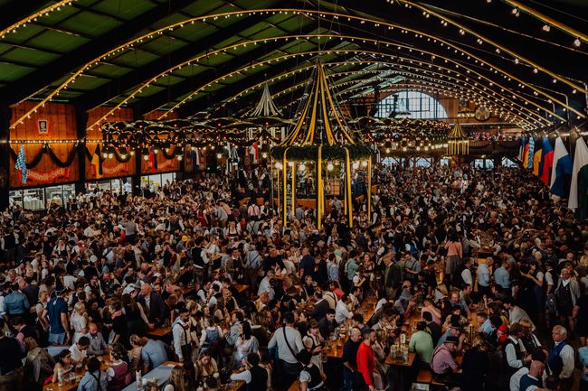 Innenraum der Augustiner Festhalle, lebhaft gefüllt mit fröhlichen Menschen